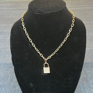 Gold tone paperclip style necklace with diamond studded lock.